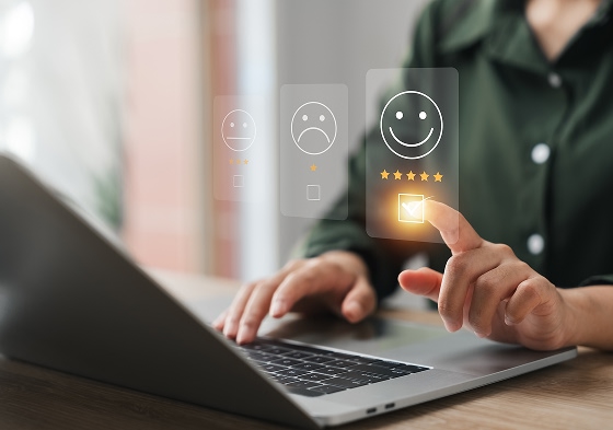 Personne évaluant un service sur un ordinateur portable avec une interface de satisfaction et une note de cinq étoiles