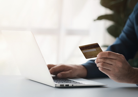 Personne utilisant un ordinateur portable avec une carte bancaire pour effectuer un achat en ligne