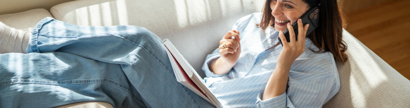 Femme assise sur un canapé et utilisant son smartphone pour communiquer